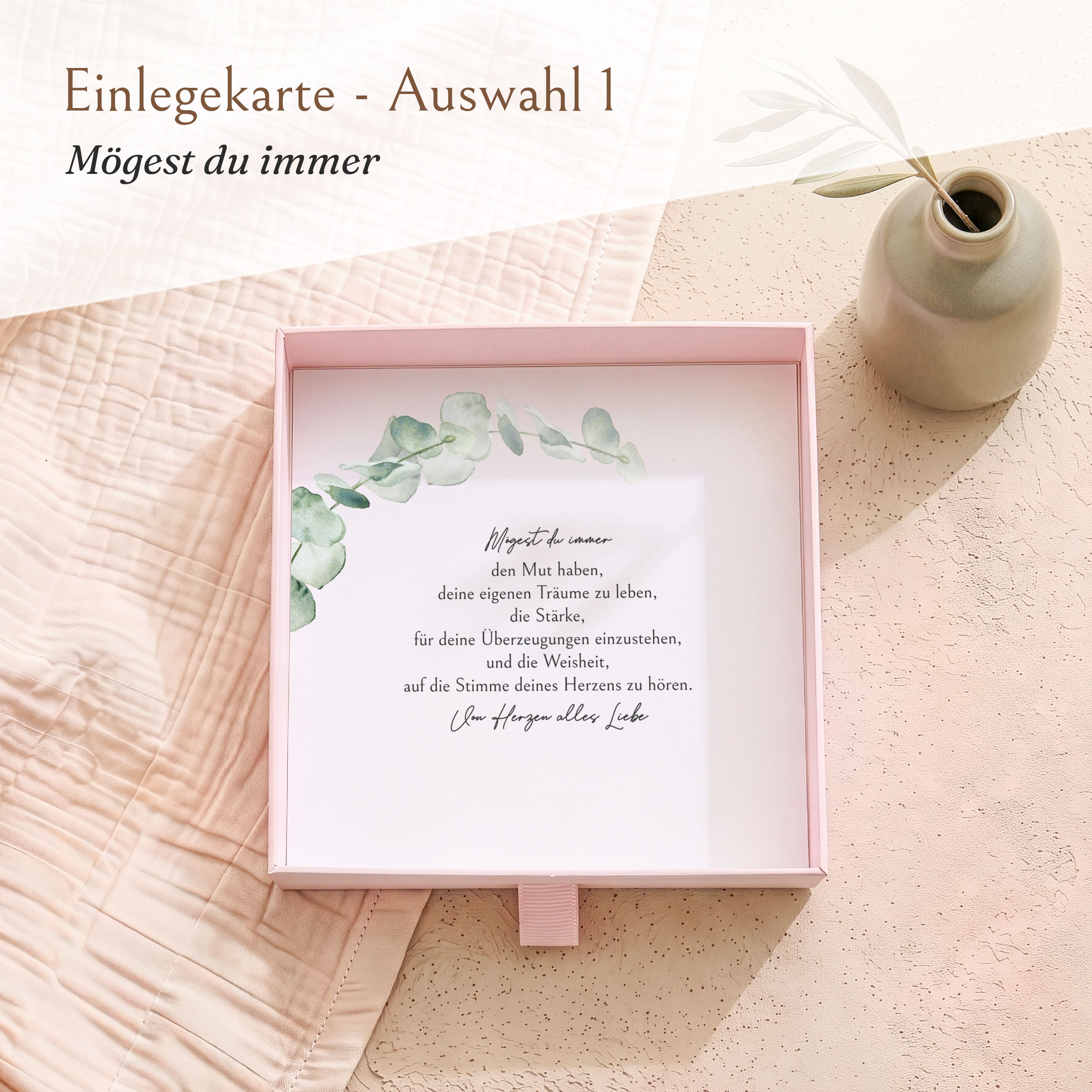Offene rosa Geschenkbox aus strukturiertem Karton zur Konfirmation, mit bedruckter Einlegekarte mit "Mögest du immer"-Spruch und Eukalyptus-Design.