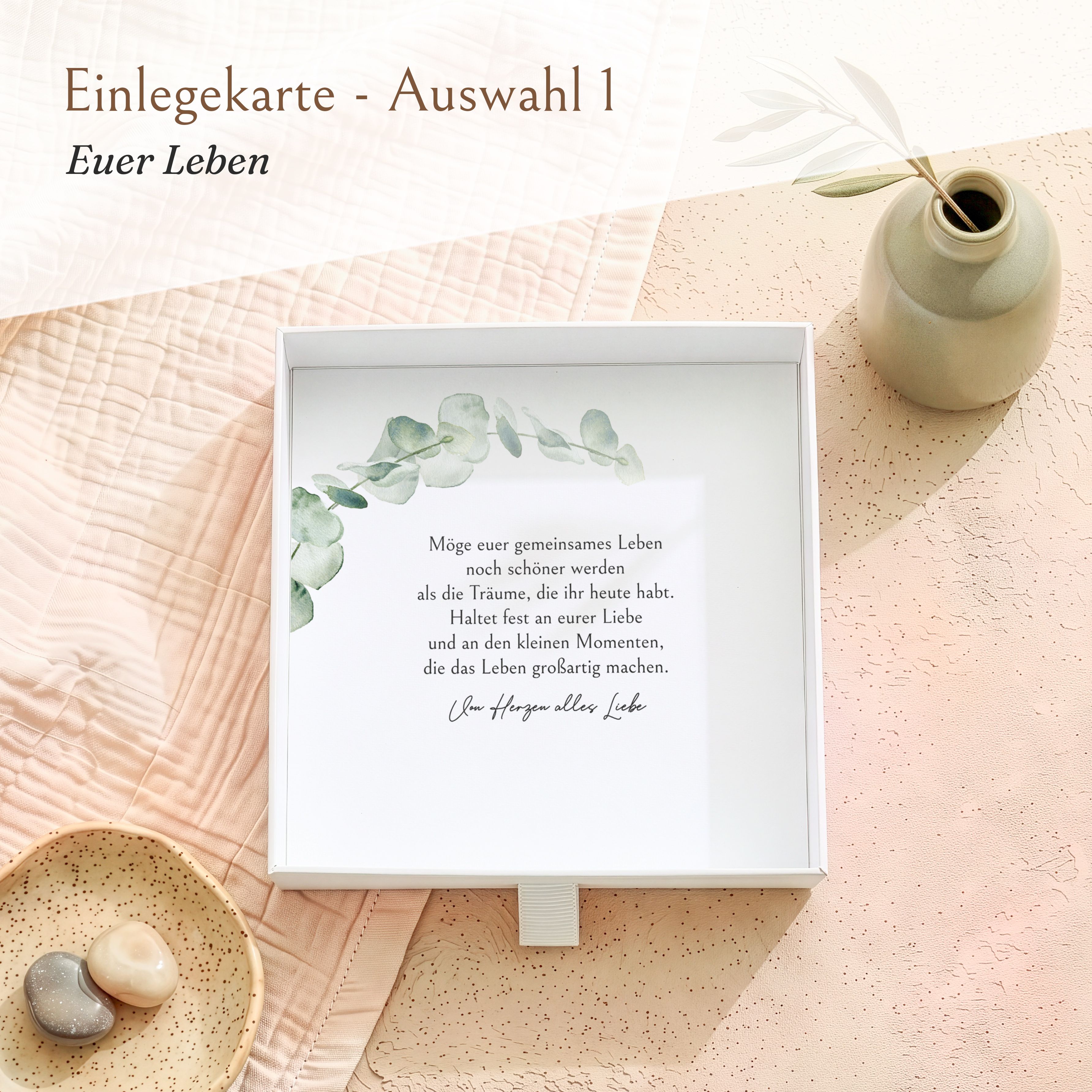 Weiße, geöffnete Geschenkbox aus Karton mit einer beschreibbaren Einlegekarte. Die Karte zeigt einen Eukalyptuszweig und einen Glückwunschtext zur Hochzeit.