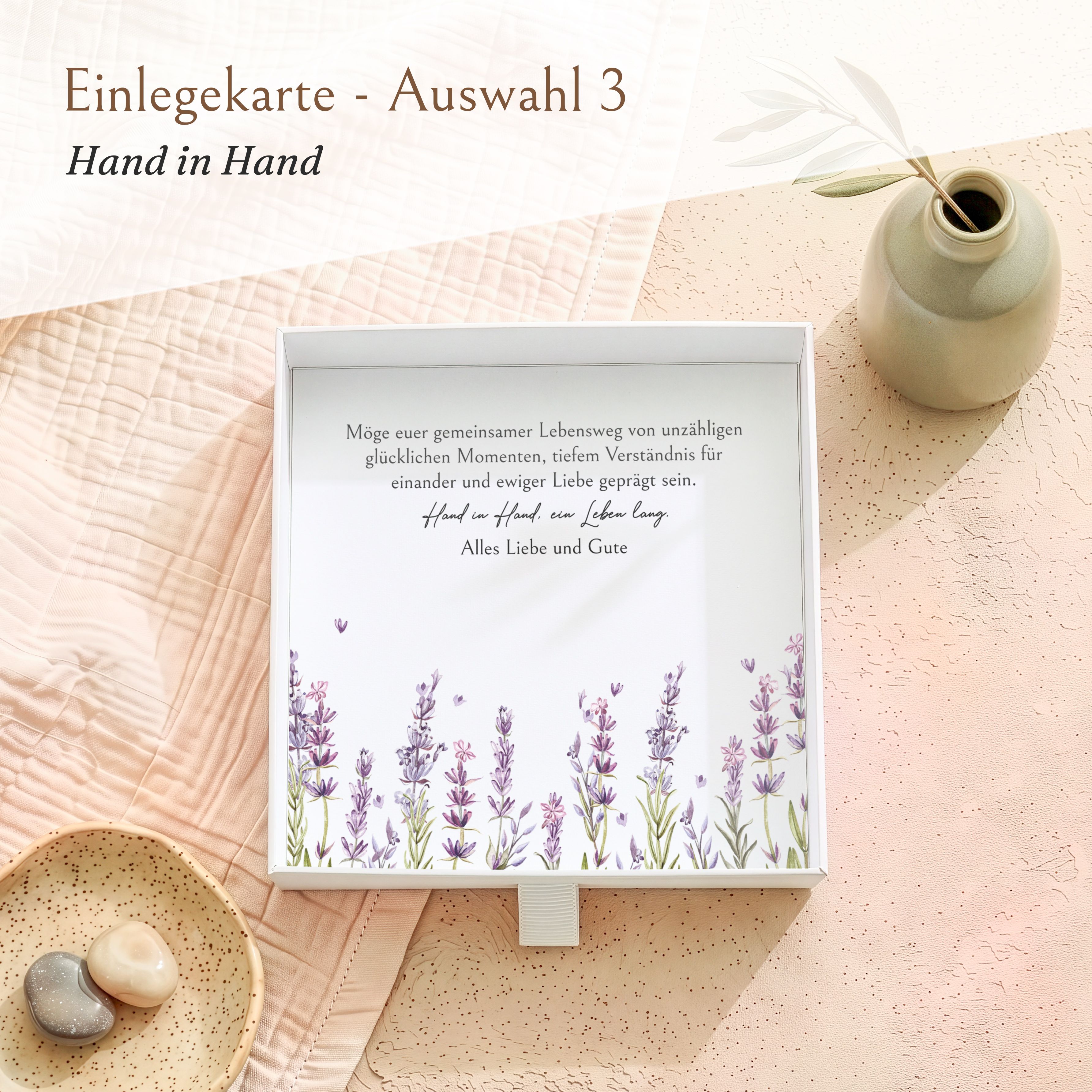 Offene weiße Geschenkbox aus Karton für Hochzeitsgeschenke. Innen liegt eine bedruckte Einlegekarte mit lila Lavendelmotiv und dem Spruch 'Hand in Hand'.