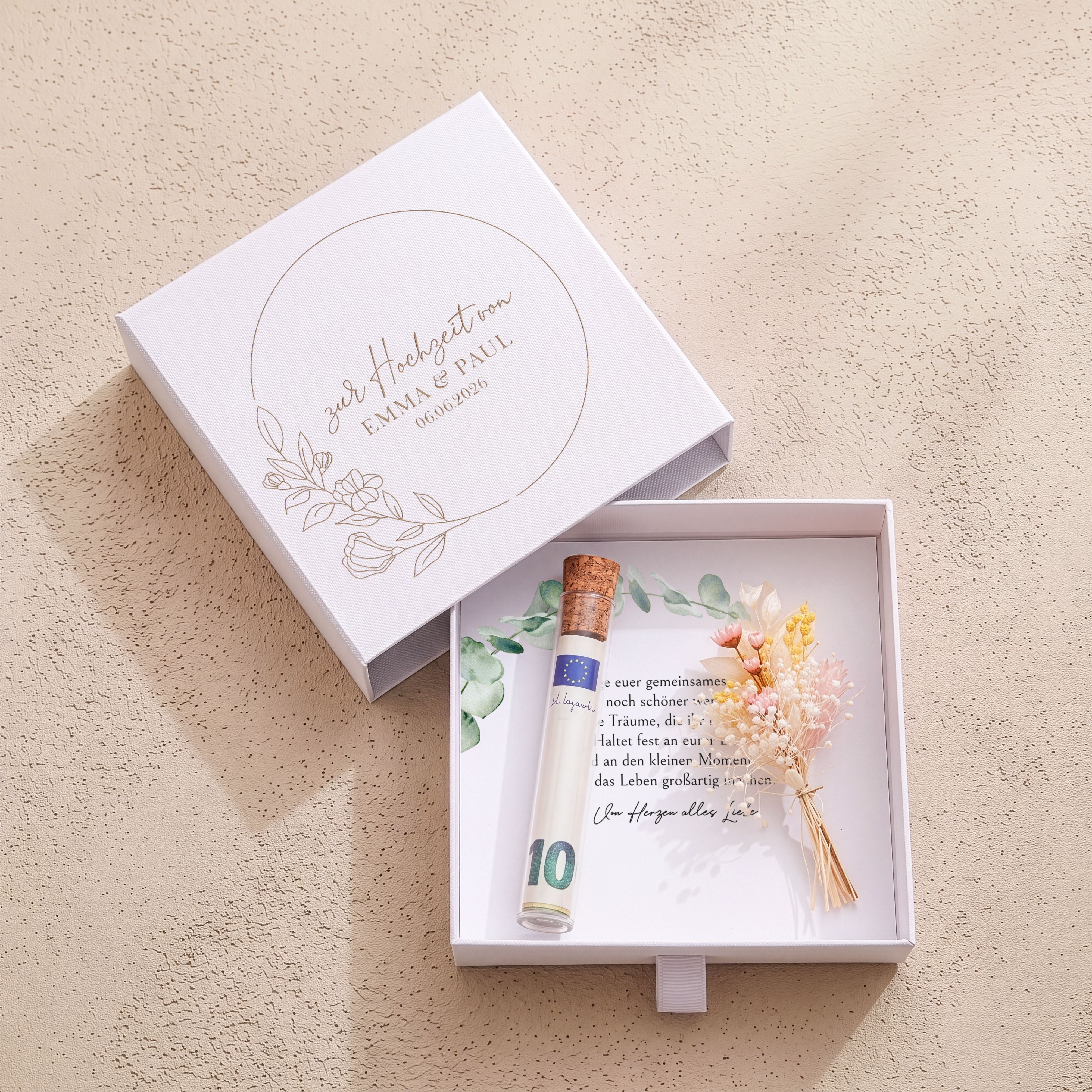 Weiße Geschenkbox aus Karton mit graviertem Blütenkranz auf dem Deckel. Enthält Glasröhrchen, bedruckte Einlegekarte und Trockenblumenstrauß.