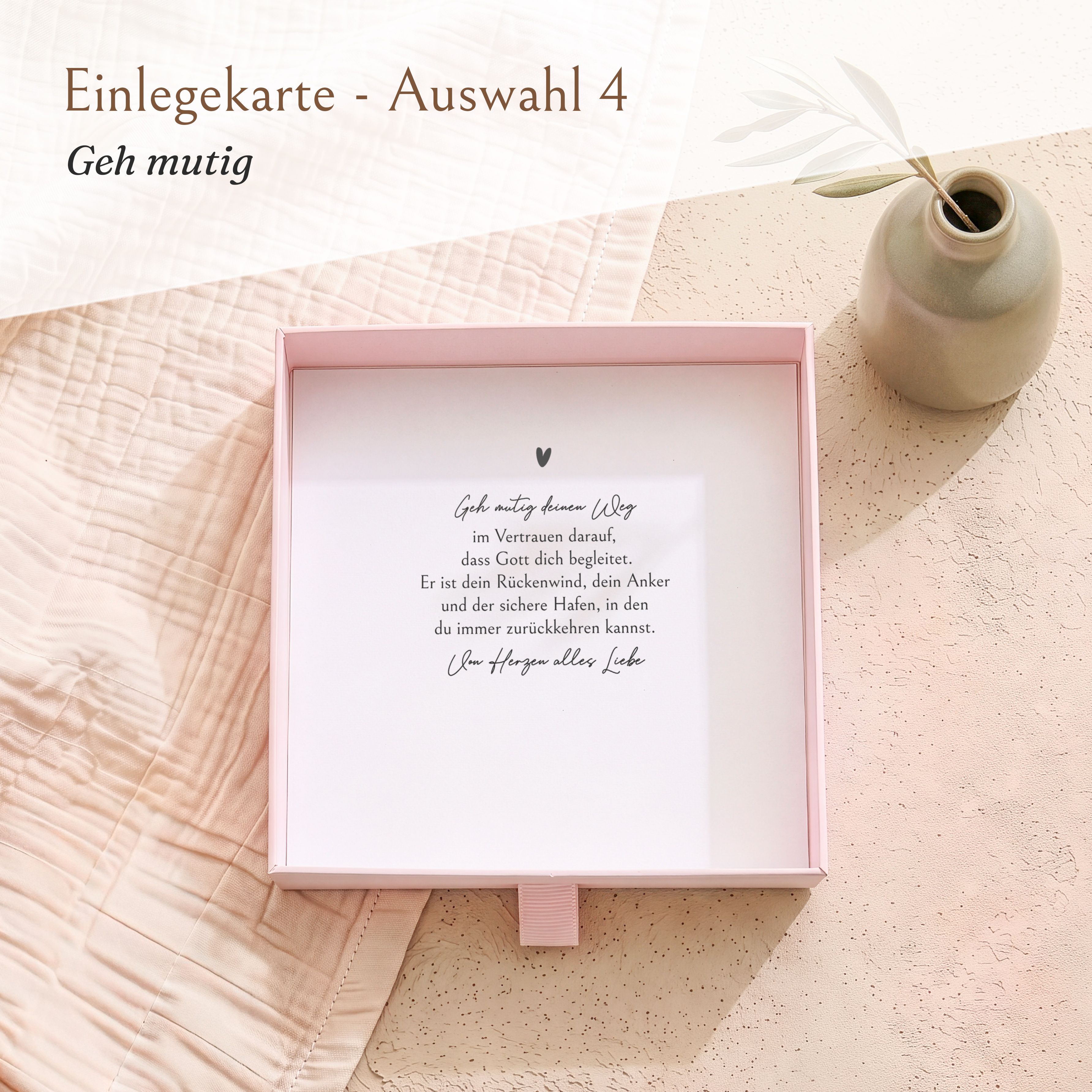 Offene rosa Geschenkbox aus strukturiertem Karton für die Konfirmation, innen eine weiße Einlegekarte mit dem Spruch „Geh mutig deinen Weg“.