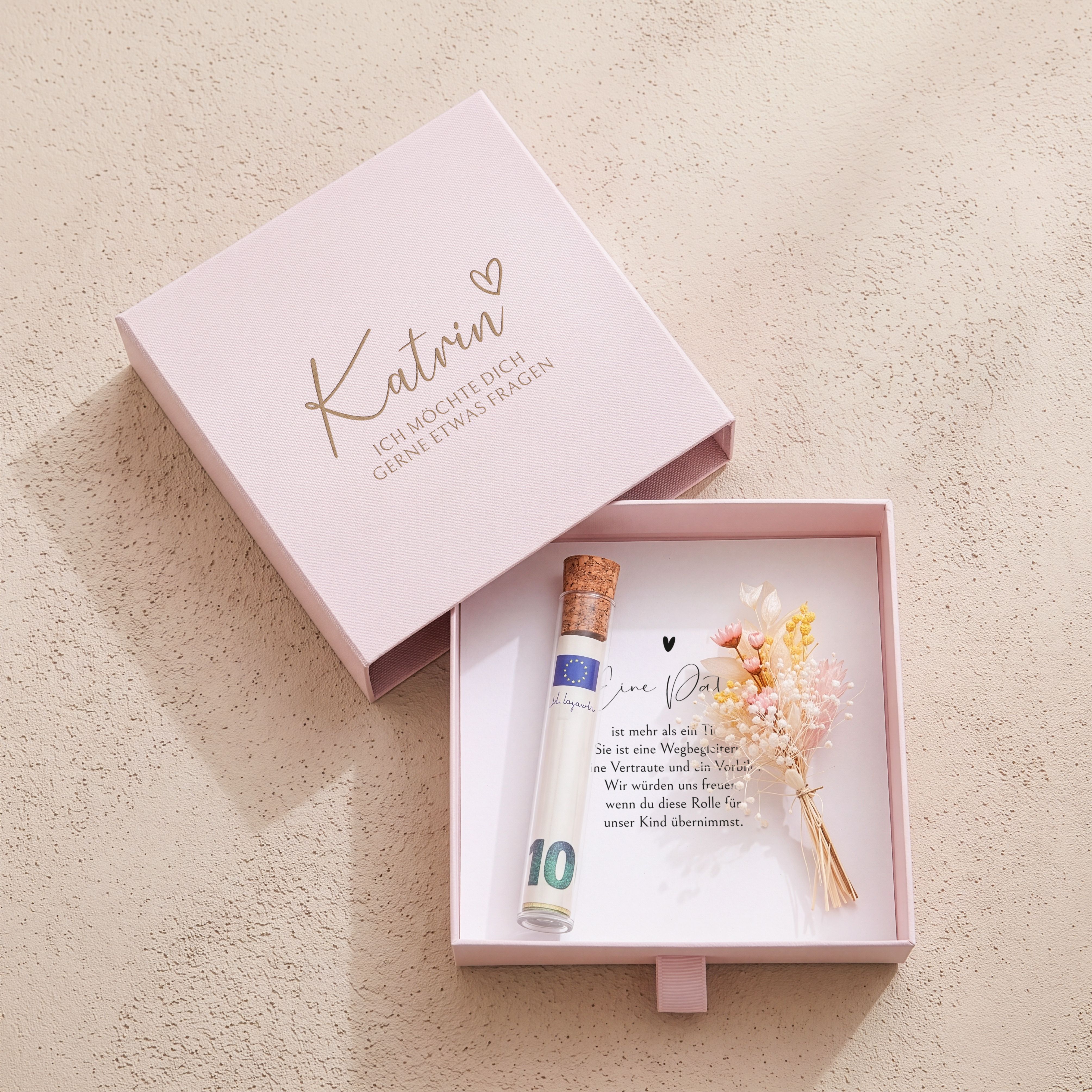 Rosa Karton-Geschenkbox mit Patenfrage-Gravur (Herz, Spruch). Innen: Einlegekarte, Glasroehrchen, Trockenblumen.