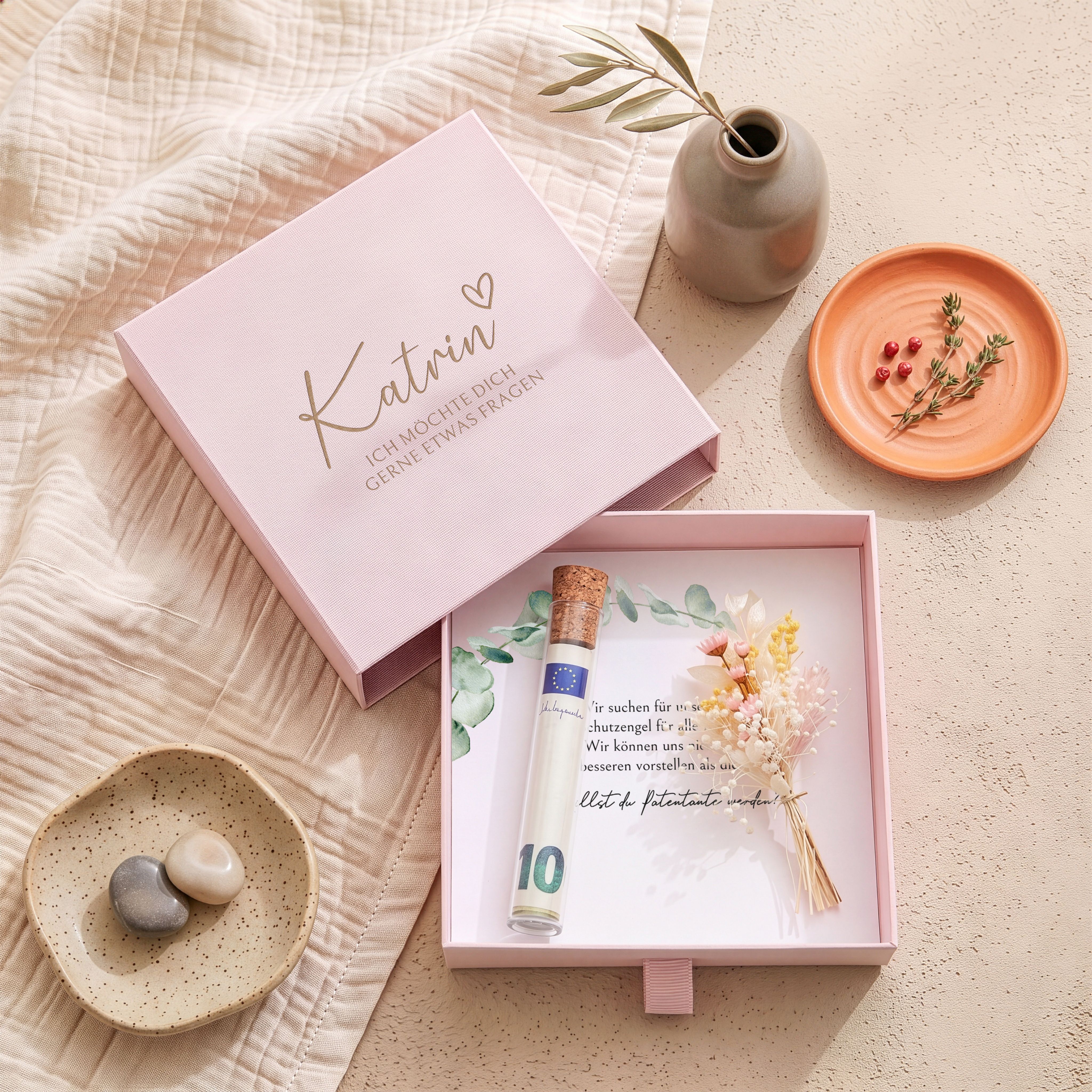Rosa Karton-Geschenkbox für Patenfrage. Deckel mit Namensgravur, Herz und Text. Innen bedruckte Karte, Glasröhrchen mit Korken und rosa Trockenblumen.