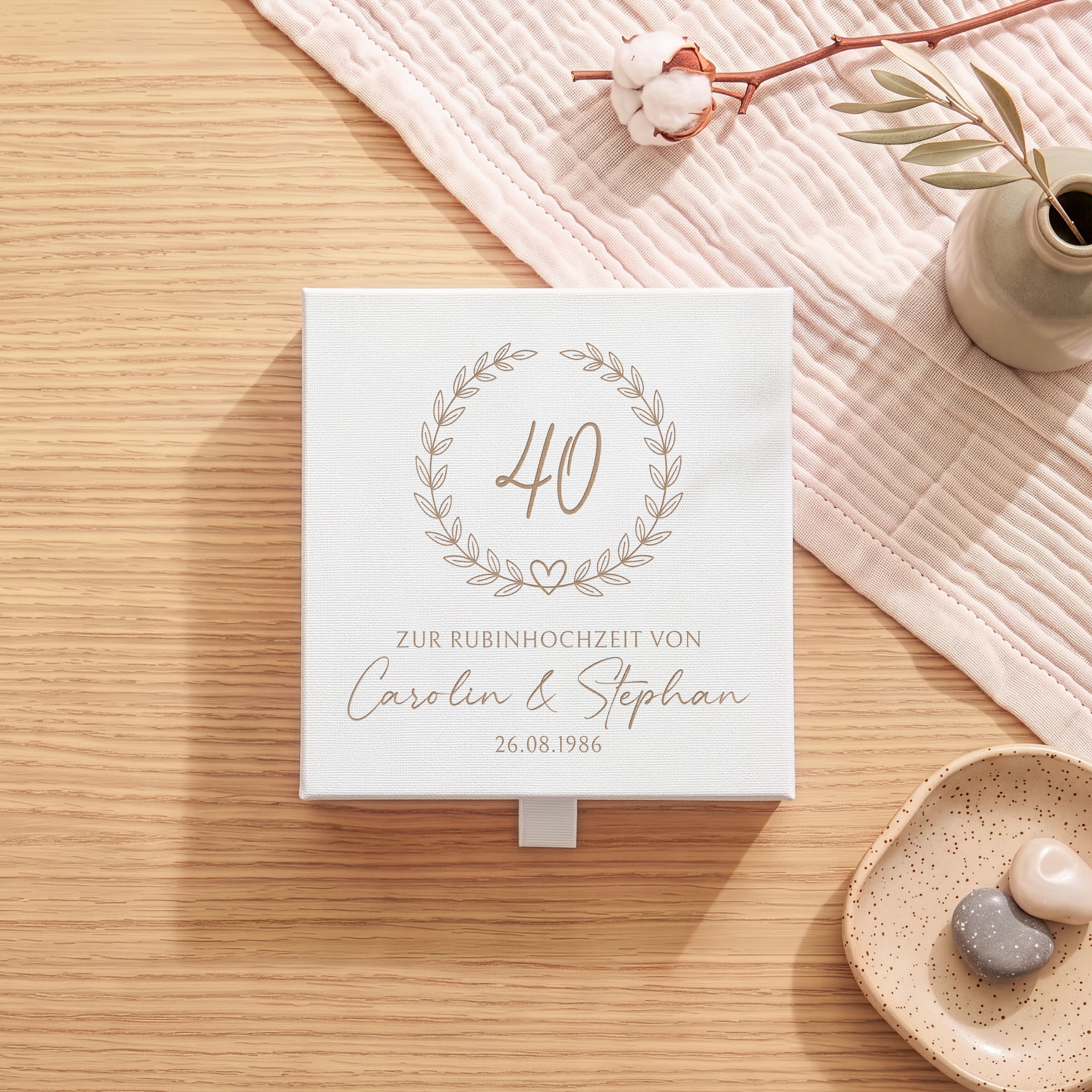 Weiße Geschenkbox aus strukturiertem Karton mit eleganter Lasergravur eines Blätterkranzes und der Jubiläumszahl 40 zur Rubinhochzeit.