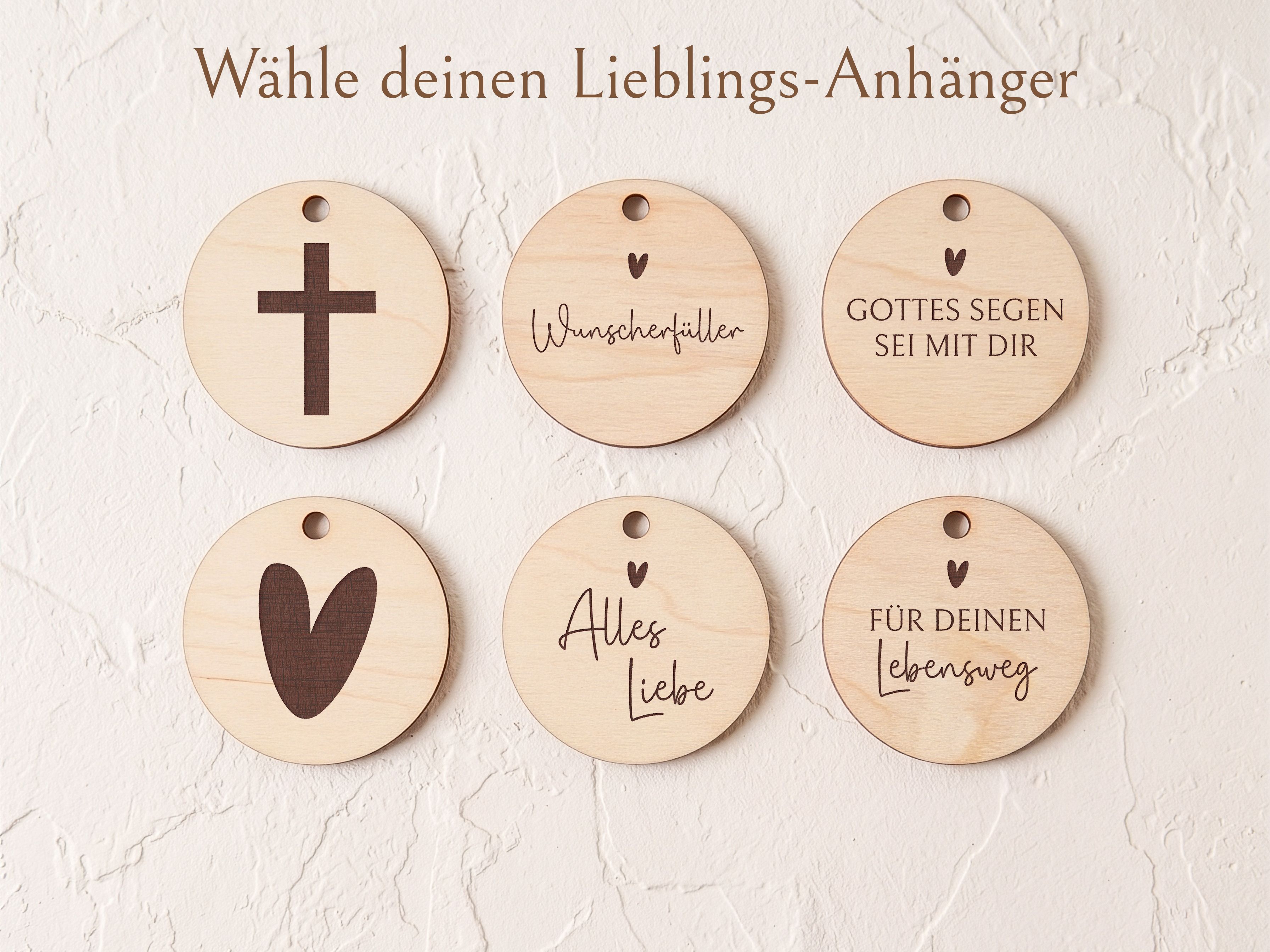 Sechs helle runde Holzanhänger mit dunkler Gravur zur Auswahl für Kommuniongeschenke. Motive sind ein Kreuz, ein Herz und Texte wie 'Wunscherfüller' oder 'Gottes Segen sei mit dir'.