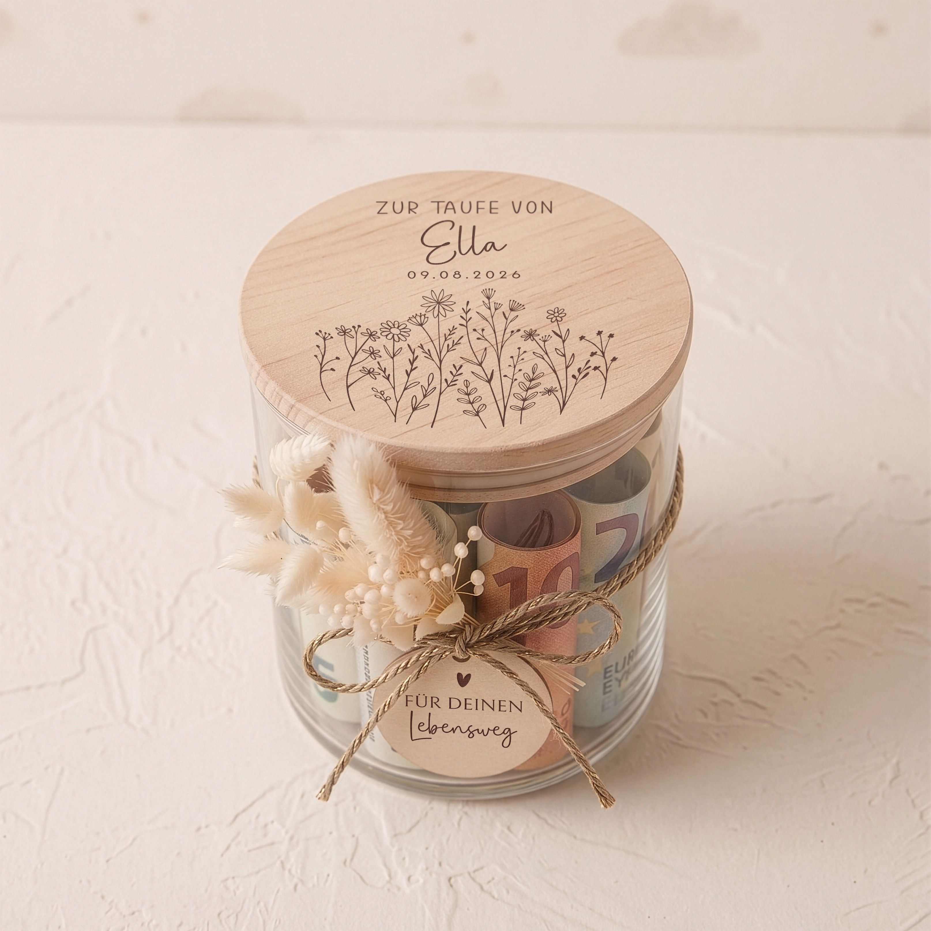 Personalisiertes Vorratsglas zur Taufe. Gravierter Holzdeckel mit Blumenwiese-Motiv, beige Trockenblumen und Holzanhänger.